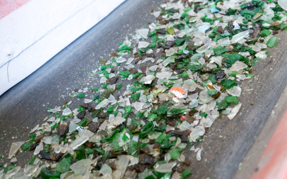 Pieces of broken glass items on a conveyor belt in a recycling plant