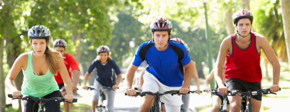 a group of male and female cyclists riding in the sunshine with helmets and summer clothing