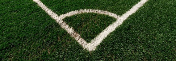 the corner of an artificial playing field with white markings