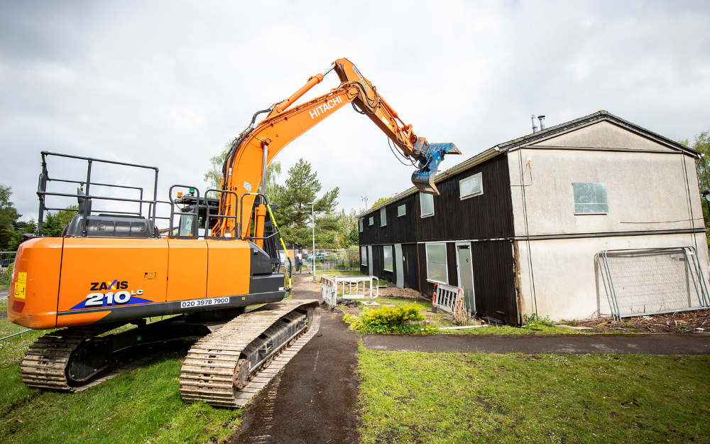 A digger about to move its arm through a house as part of the Gorse Ride demolition