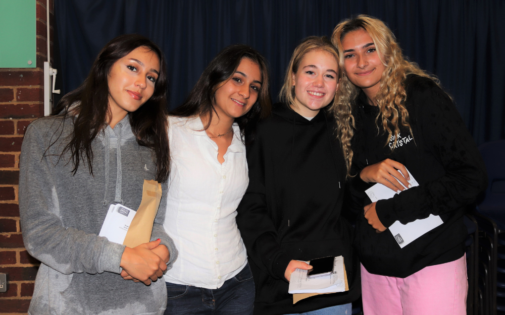 Four girls from Emmbrook School smile to the camera after collecting their GCSE results