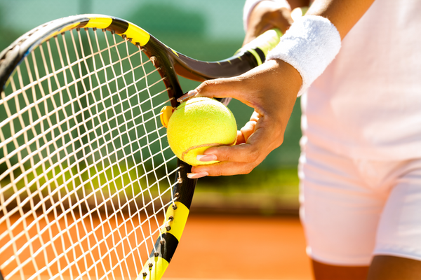 Close up of someone preparing to hit a tennis ball with a racket