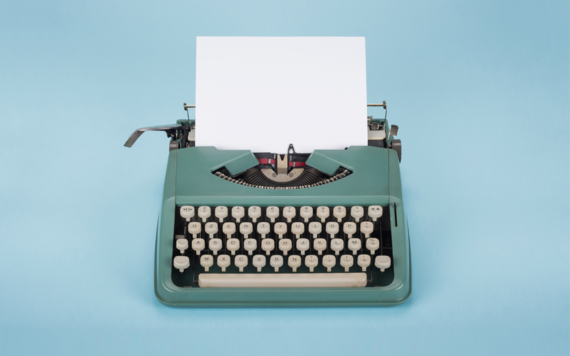 A typewriter with a blank sheet of paper sticking out the top