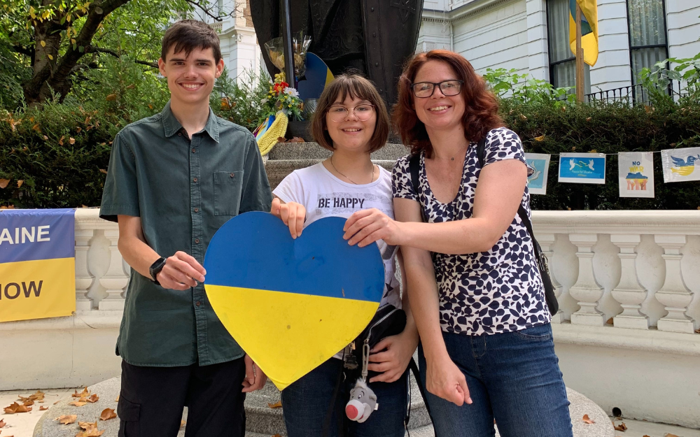 A Ukrainian family holding a heart shape displaying the Ukrainian flag