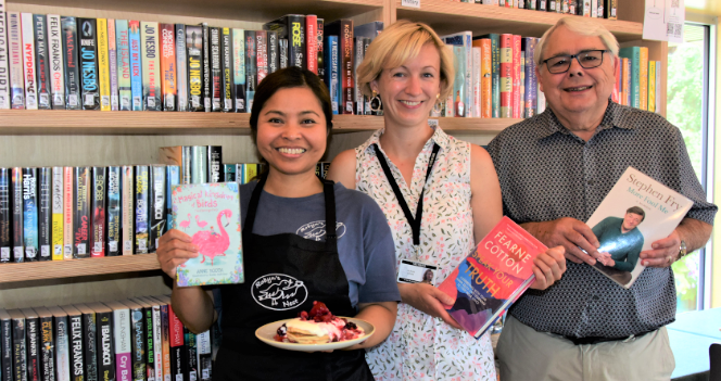 three people holding books to the camera and smiling