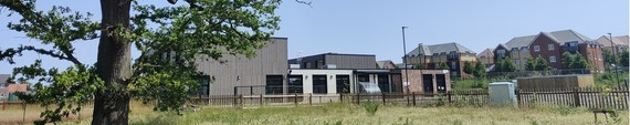 ultra-wide image of the new St Cecilia's Primary School in north Wokingham, seen from green land behind the site