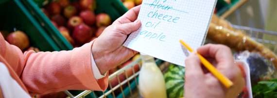 close up of a hand ticking off items on a shopping list in a supermarket