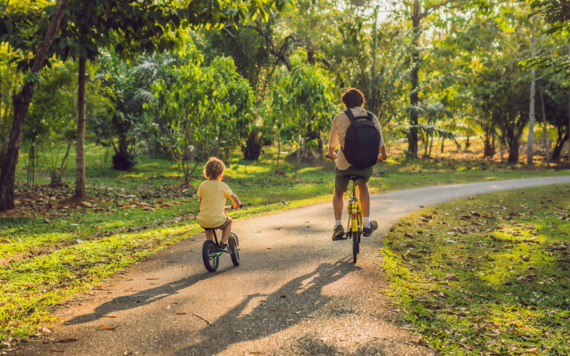 a man and a child cycling on a path in a country park