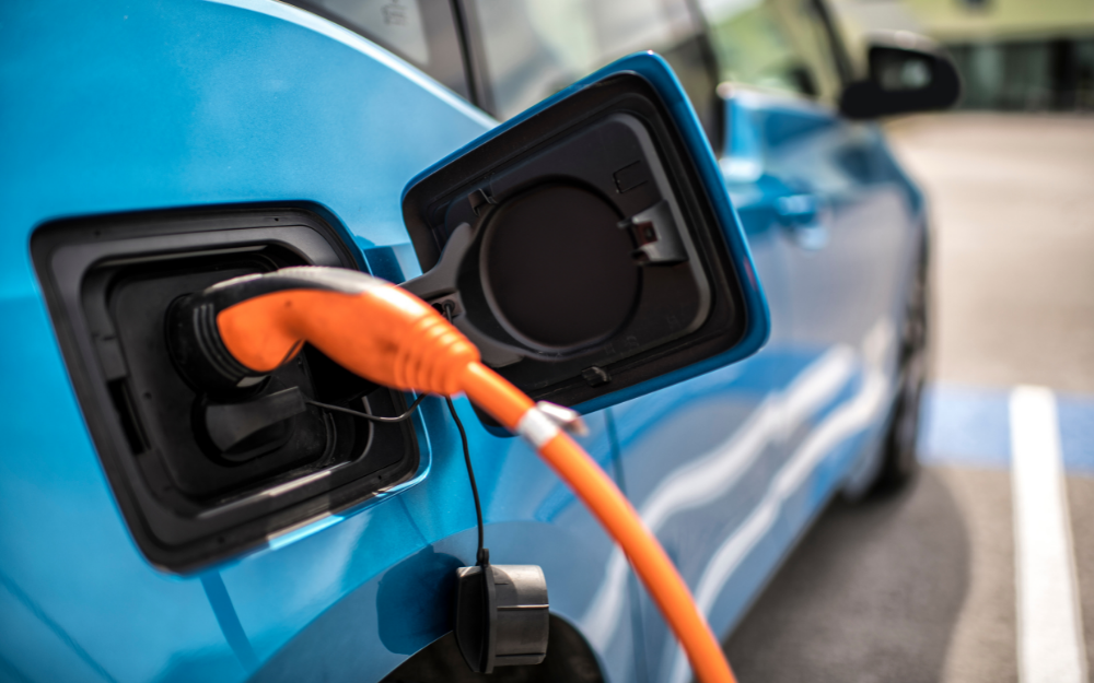 An electric car charger plugged into a vehicle at the roadside