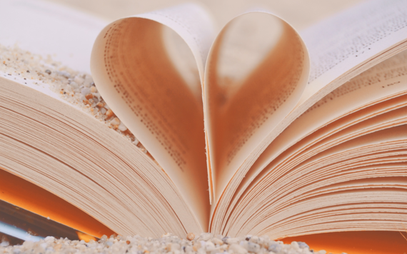 An open book viewed from it's edge with central pages folded inwards to make a heart