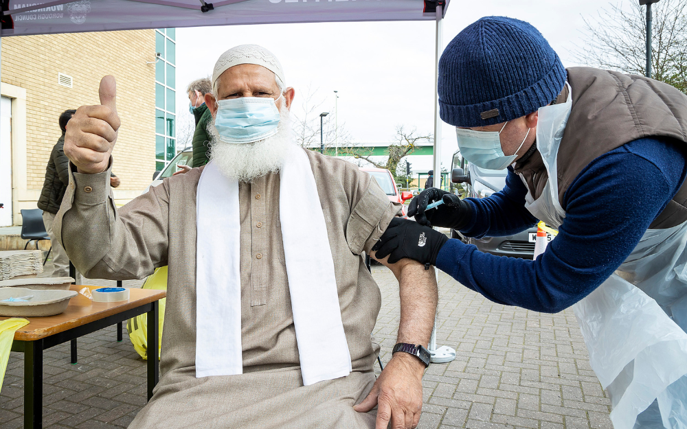 A man in a face mask puts his thumb up as he gets his Covid-19 vaccine