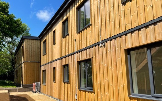 shot of the new modular housing at Grovelands - two timber-clad portable cabins stacked doubly with a staircase leading to the upper one