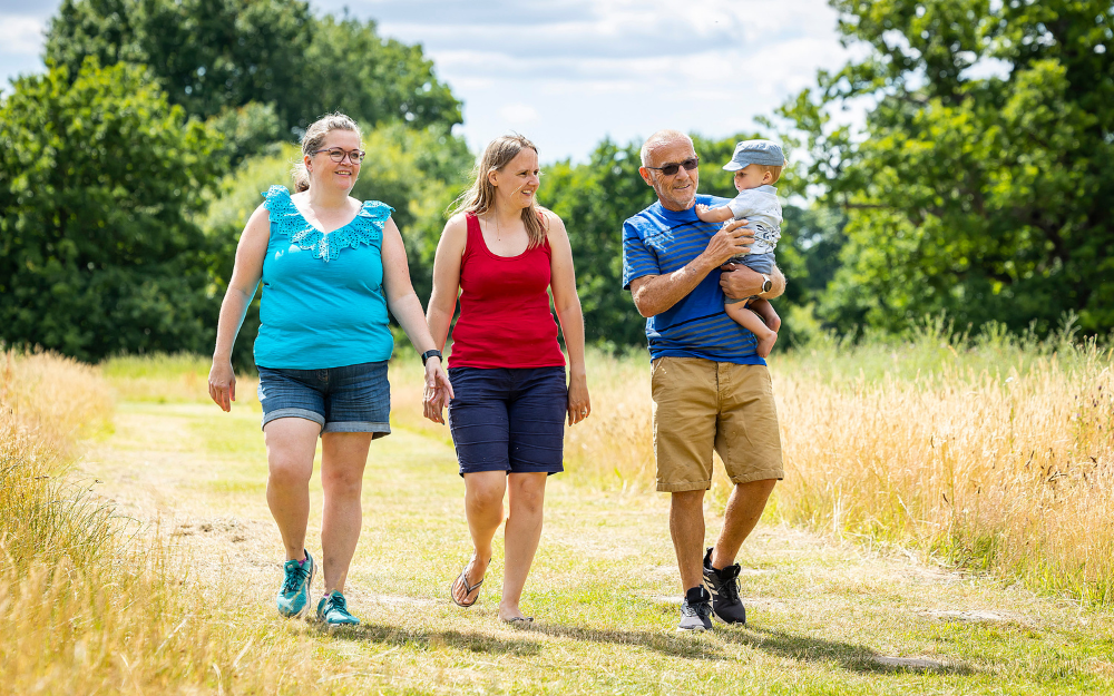 Three people, one holding a young child, walk along a countryside path in Wokingham borough