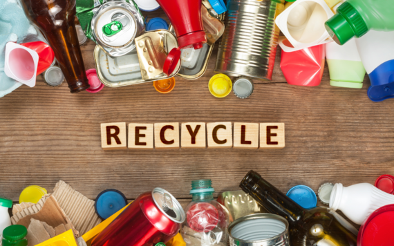 A top view of a table with many recyclables and in the centre it reads recycle