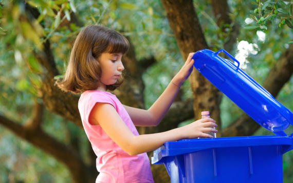  A girl putting a plastic bottle into a blue bin