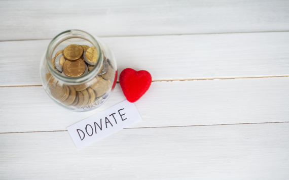 A jar of coins with the word donate in the front and a heart beside it