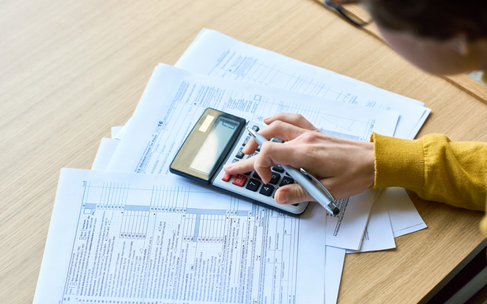 A person with bills in front of them using a calculator