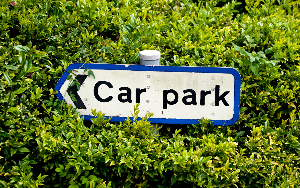 A sign pointing left, which reads 'car park' surrounded by greenery