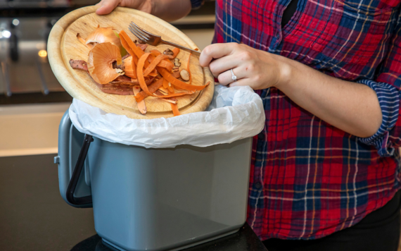 Some food waste being put into a kitchen caddy