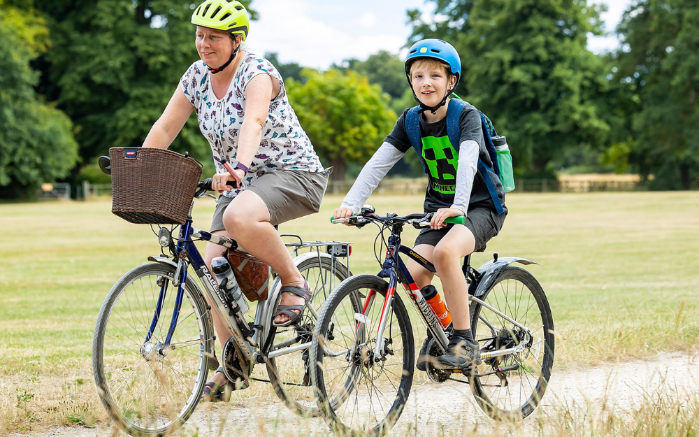 A woman and a boy cycle alongside an off-road countryside cycle route