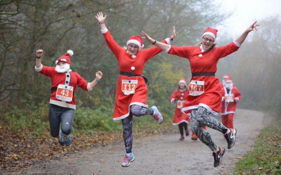 Runners dressed in a Santa suit jumping up on a path at Dinton Pastures Country Park