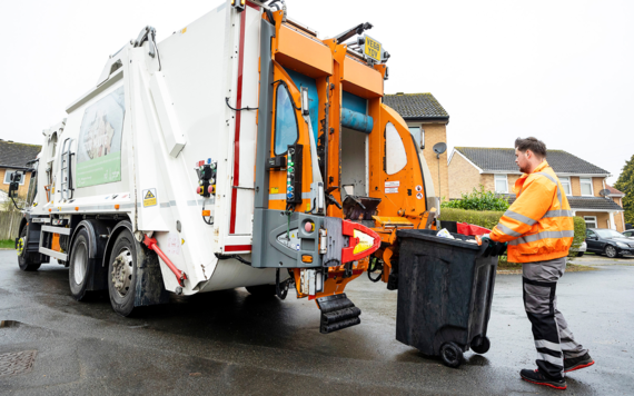 A crew member putting bags of wastes into a waste truck