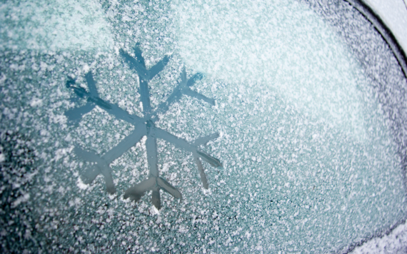 Close up of frosty car windscreen with a snowflake drawn into the frost