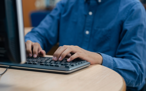  A man sitting in front of a computer and typing on the keyboard