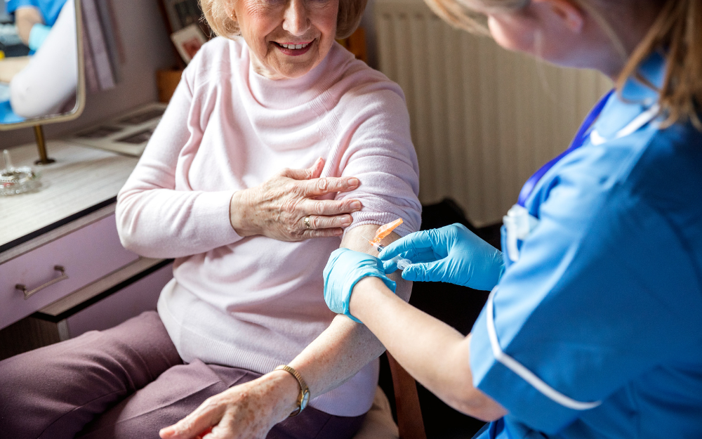 An older women gets a vaccine into her upper warm from a health worker