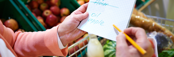 close up of a hand ticking items off a shopping list in a supermarket