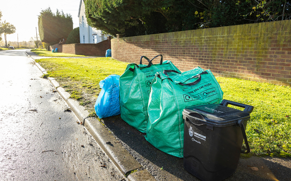 A food waste caddy, green recycling bags and blue waste bag at the kerbside