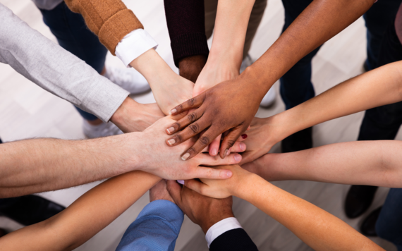 A group of people all putting their hands in a circle