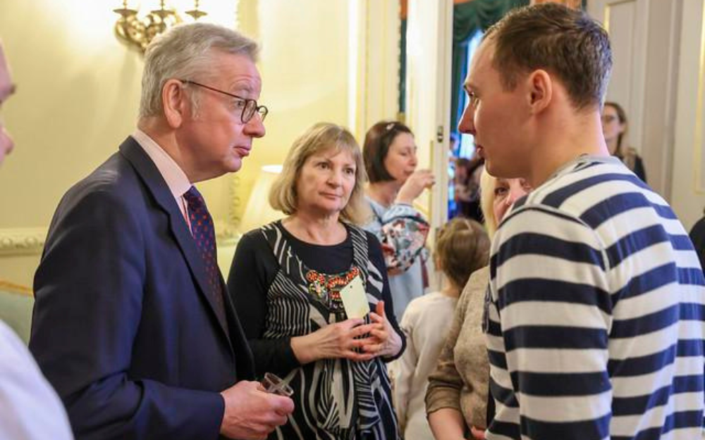 Sasha, one of the borough's Ukrainian guests, talks to Michael Gove as another guest Joanne watches on