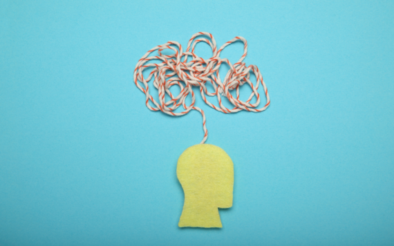 A tangle of string is formed above a cut out paper head 