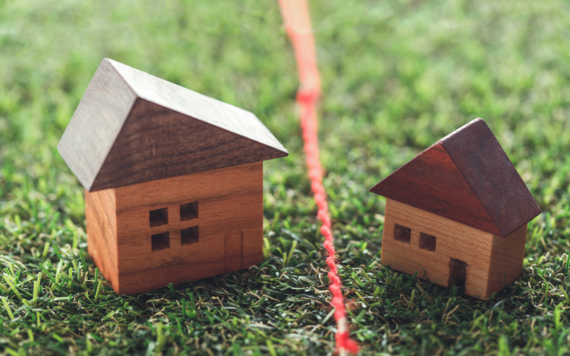 Photograph of two small wooden toy houses with a red rope indicating a boundary