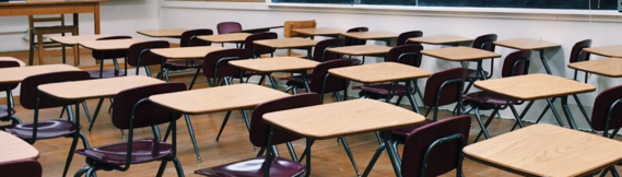 a few rows of empty desks in a classroom