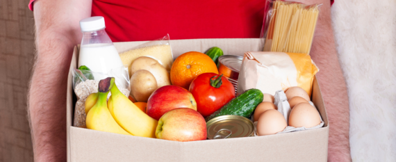 close up on a pair of hands holding a cardboard box filled with food