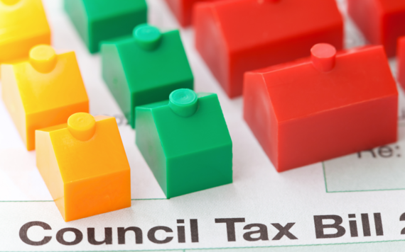 Photo shows council tax bill with plastic model houses placed on top of it