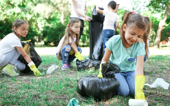 Some children picking up litter in an open green space