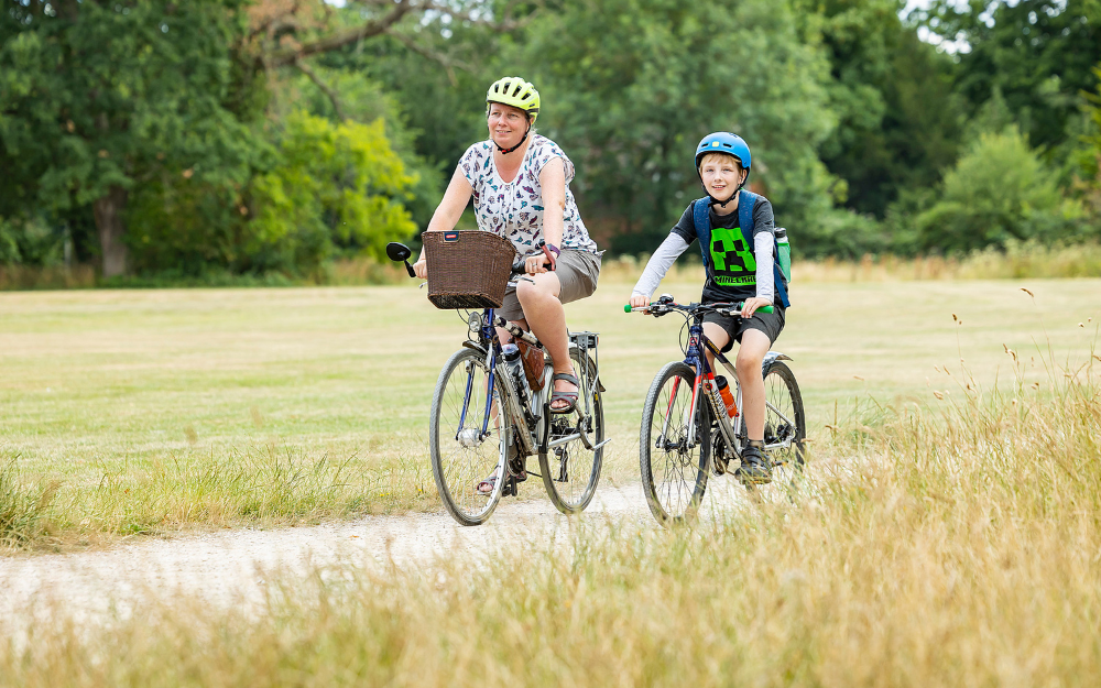 A woman and a boy cycle together along a cycle path in a park in Wokingham Borough