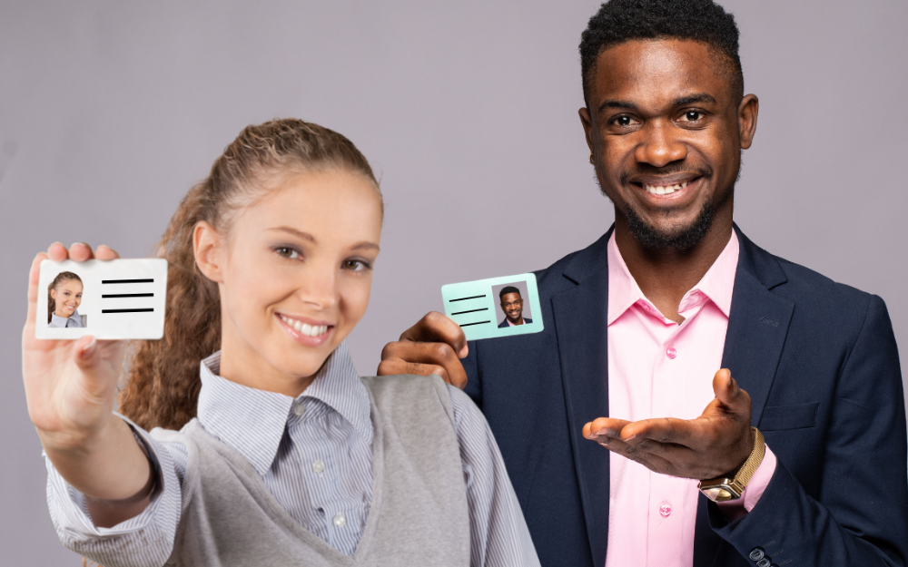 A man and a woman hold ID cards out in front of them, smiling at the camera