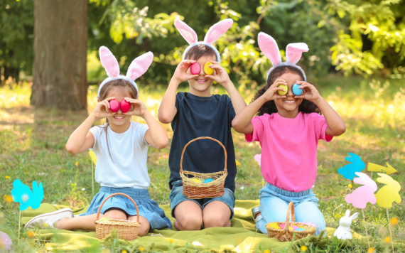 Three children sitting on the grass and having fun with some Easter eggs