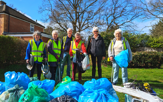 A group of Adopt a Street volunteers posing in front of bags of rubbish