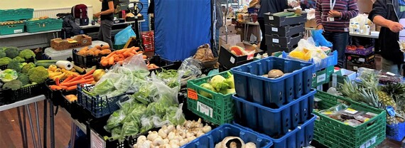 close up of a pile of fresh food on tables, mostly fruit and veg, waiting to be collected by visitors