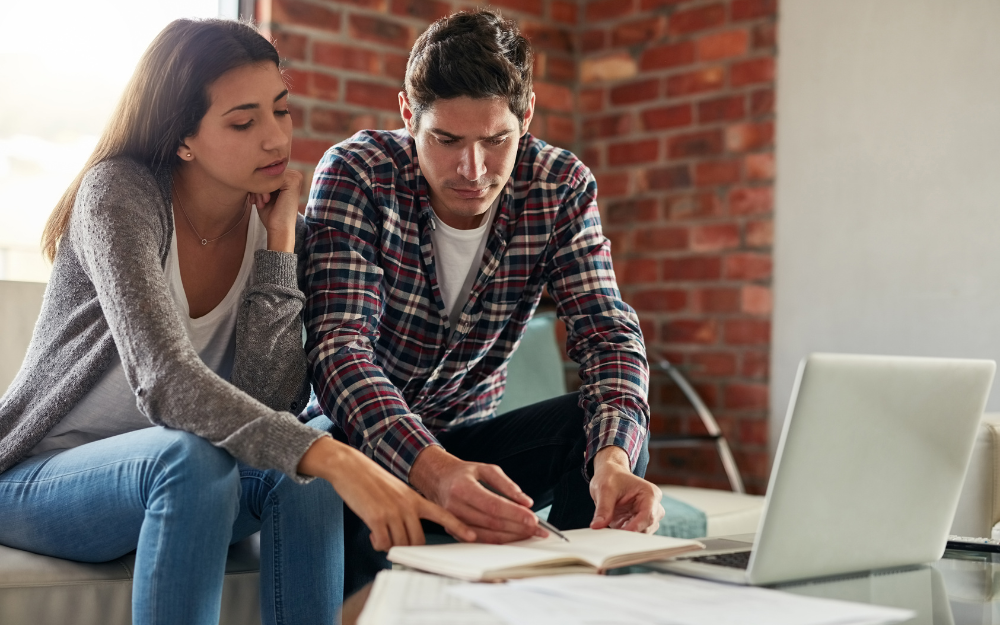 A couple at the table with laptop and bills, taking a look at their finances