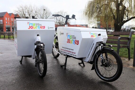 Two e-cargo bikes standing side by side on a path