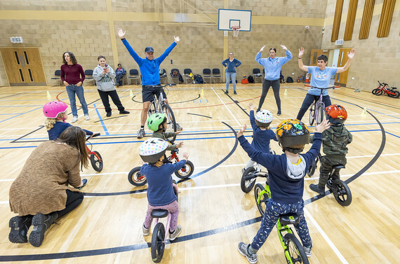 Very young children learning bike skills inside a sports hall