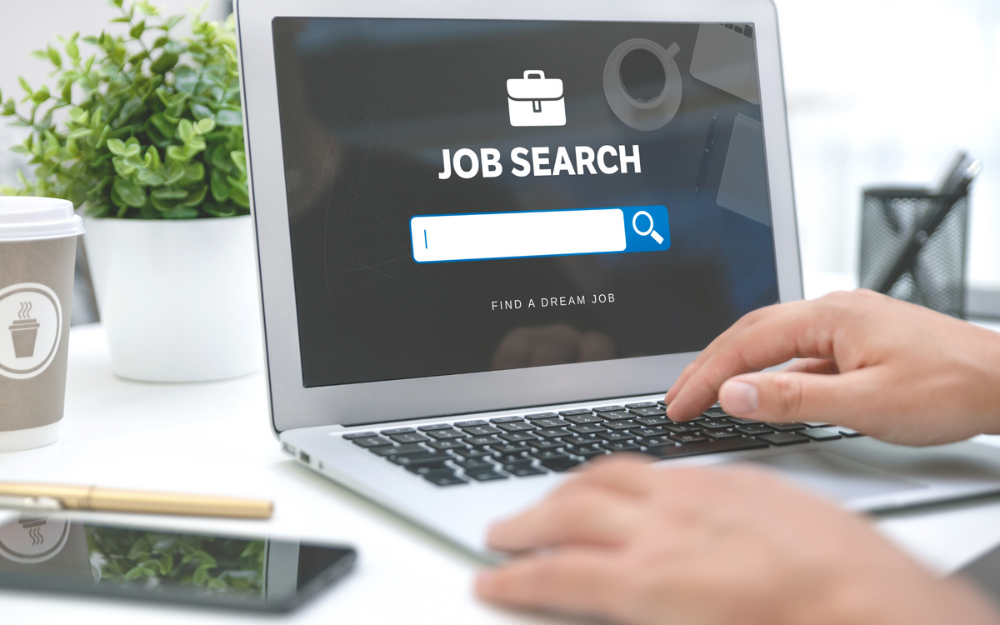 Someone using a laptop with a tab open which reads 'job search'