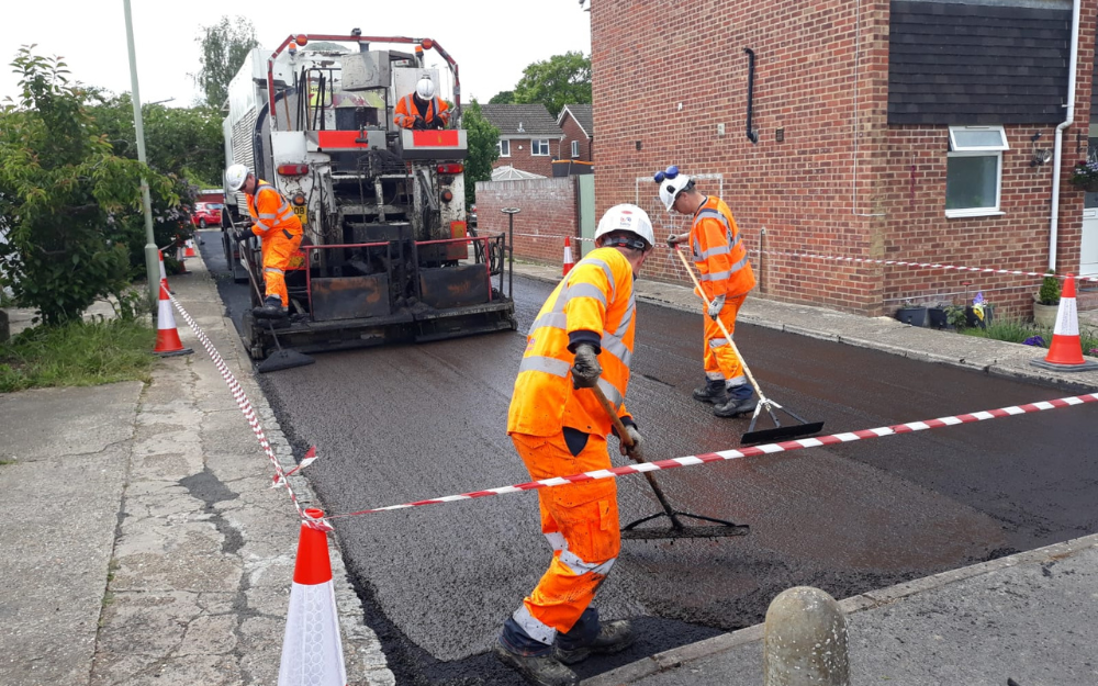 A group of road workers in hi-vis outfits and hard hats laying mico asphalt in Wokingham