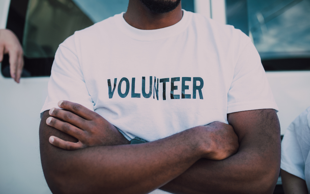 A set of crossed arms, in front of t-shirt which says 'volunteer'